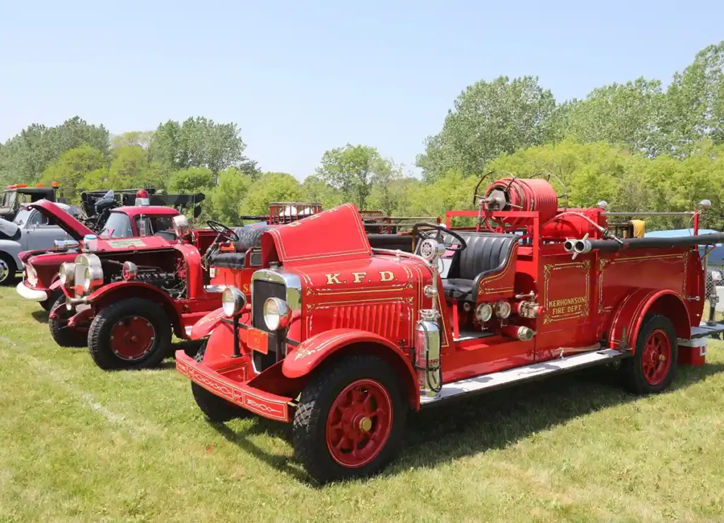 Vintage fire trucks on green grass in large field.
